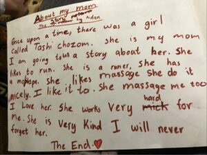 A paper with a childlike handwriting. Pictured is an essay by Tashi's 8-year-old daughter, who describes her mother with love and pride. Some words are crossed out and overwritten. Aidan has been in school since 2020.