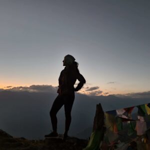 The silhouette of a young woman in front of a mountain panorama in the sunset